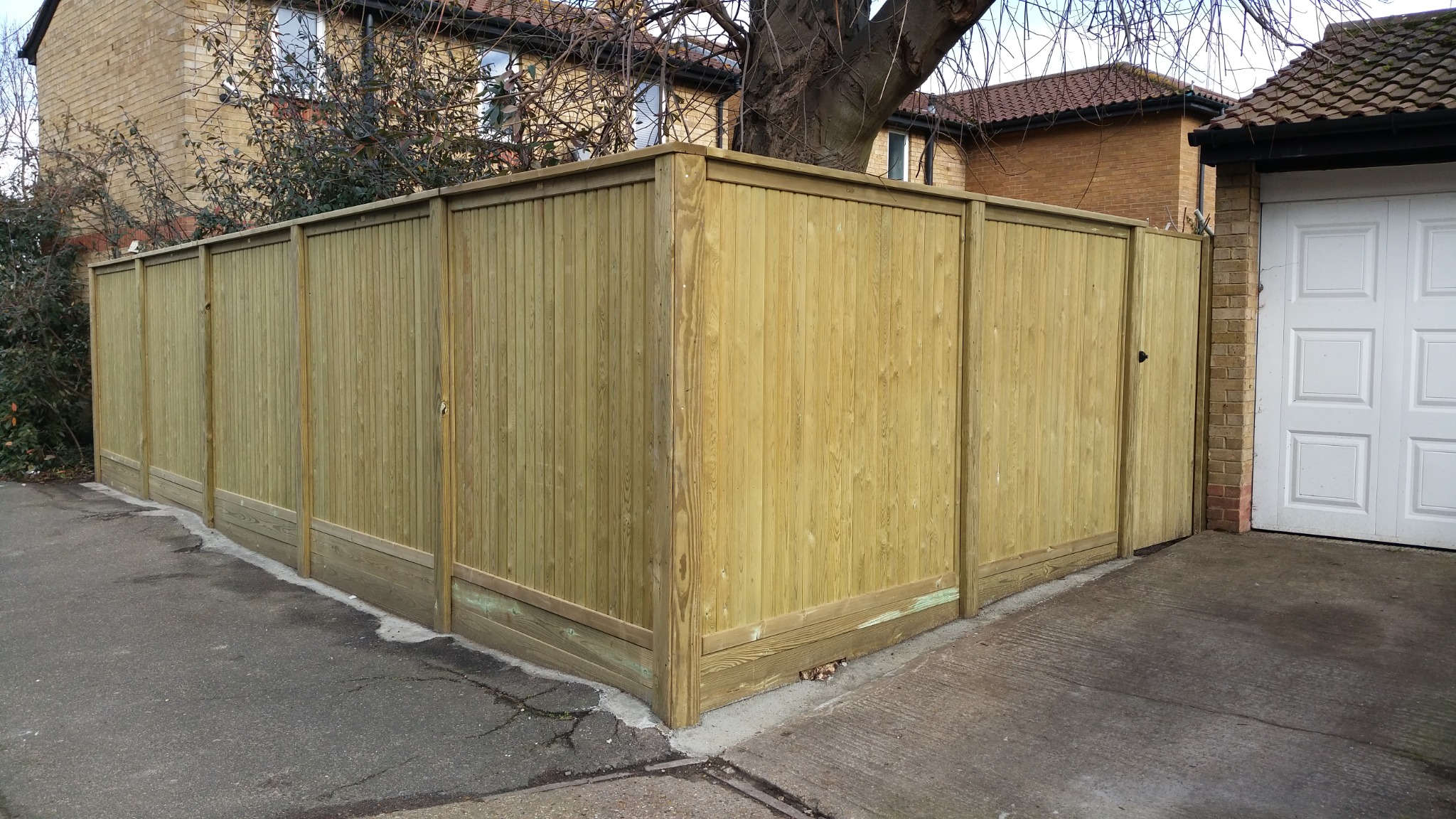 Timber fencing turning a corner beside a garage, with a matching side gate.