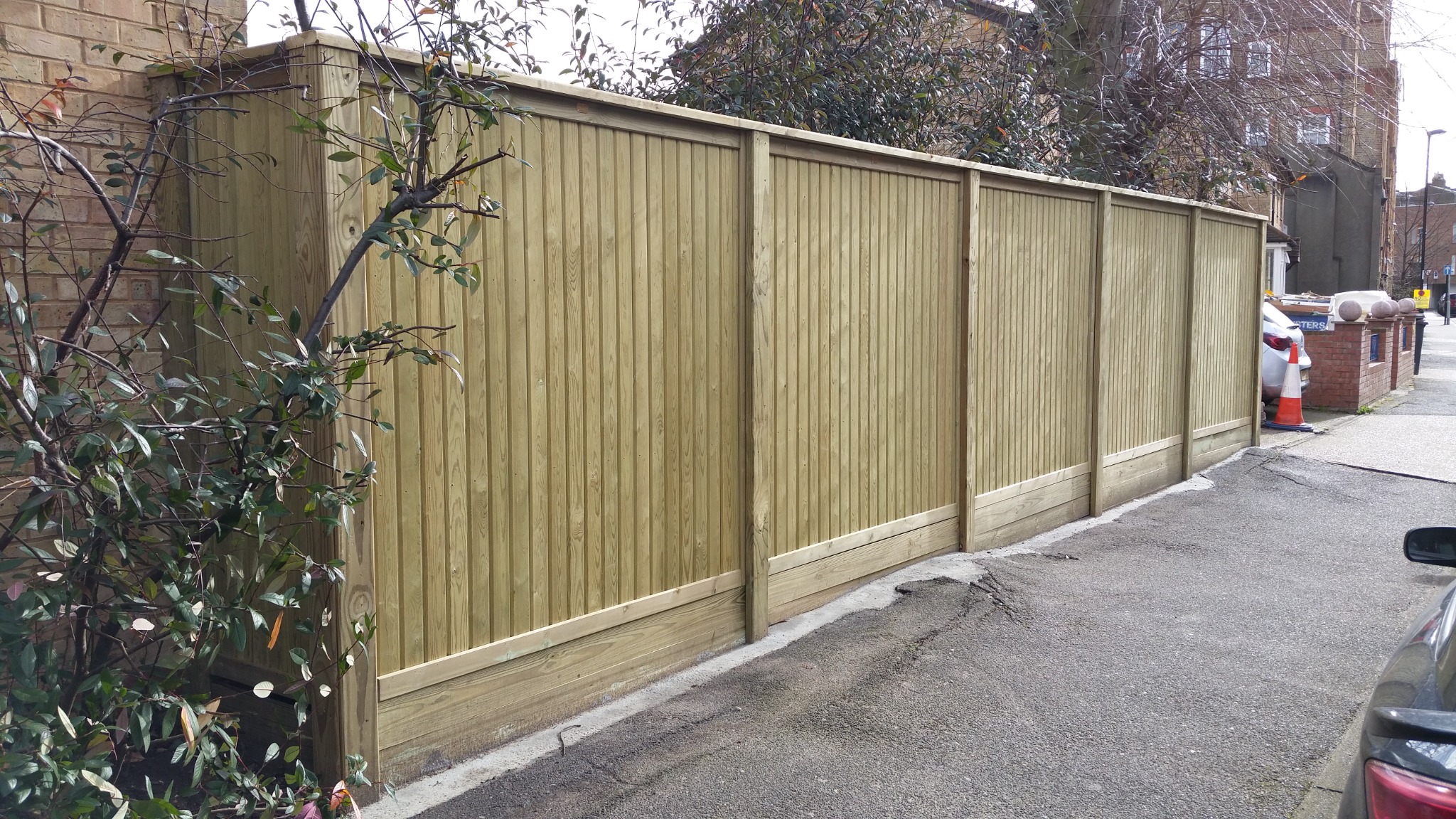 Vertical timber panels and gravel boards beside a driveway.