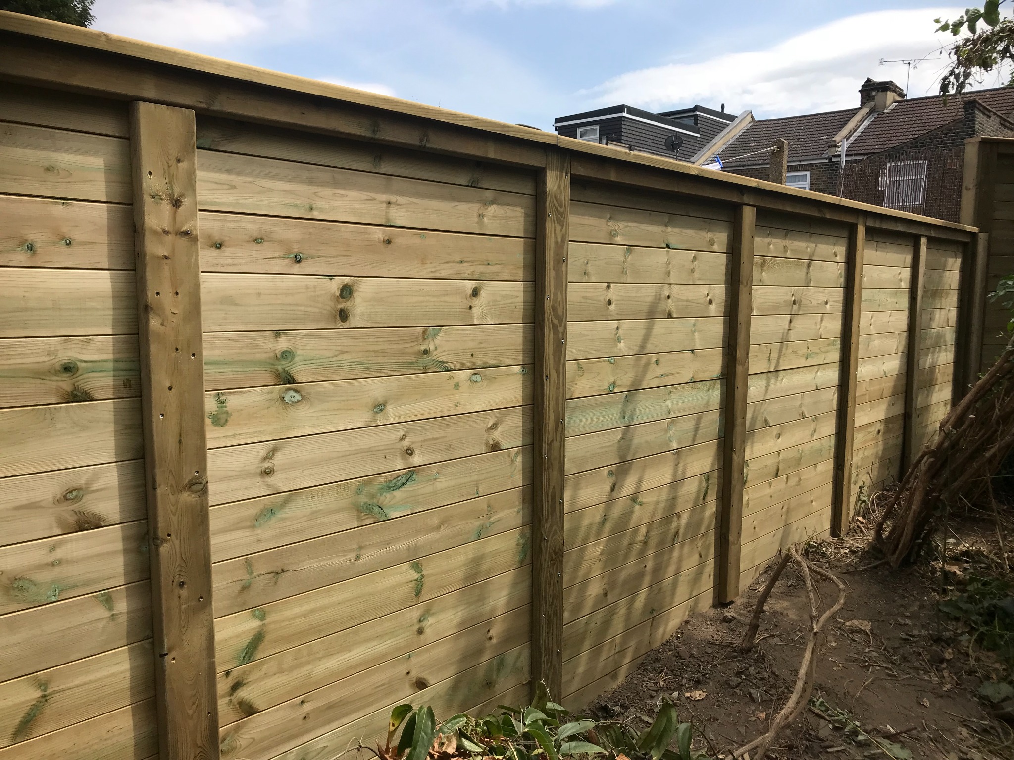 Horizontal boards between timber posts along a garden boundary.